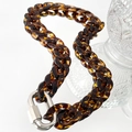 Détail macro de la chaîne en résine ambrée avec fermoir de sécurité en métal argenté - Collier marron foncé