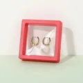 Golden textured hoop earrings displayed in a red square 3D floating film box - China Red