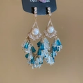Detailed macro view of vintage gold chandelier earrings with pearls and blue tassels - Gold-Blue