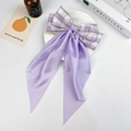 Detailed view of a purple plaid bow hair clip with long ribbons on a white decorative plate - Taro Purple