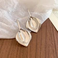 Macro detail of polished leaf-shaped silver earrings on white textured background - Silver (Silver Earring Post)