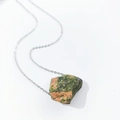Macro shot of irregular natural green and orange crystal stone pendant on silver chain - Ruby Zoisite
