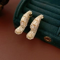 Close-up of golden teardrop wing earrings with white zircon on green velvet jewelry box - Gold