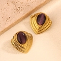 Detalle de pendientes de corazón vintage dorados con piedra púrpura sobre piedra - Morado