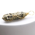 Macro view of wire-wrapped Dalmatian Jasper hexagonal pillar pendant with gold finish - Dalmatian Jasper