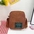 Brown corduroy crossbody messenger bag with adjustable strap and green woven label - Brown