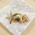 Golden starfish and seashell metal hair clip accessory on white decorative rocks - Shell Spring Clip