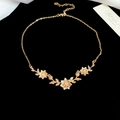 Vista macro de collar con colgante de flor y hoja dorada con strass en terciopelo - Estilo de Tres Flores y Hojas / Dorado