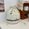 Nahaufnahme der gesteppten Kordeltasche mit Bogenstickerei und Spitzen Rüschenkante - Baby Baumwolle Schleife