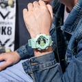 Light green dual-display sports watch with resin strap worn by a male on street background - Matcha Green
