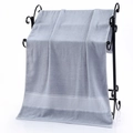 Light grey cotton bath towel with honeycomb jacquard trim hanging on a black rack - Rice Grid Jacquard Bath Towel (Grey) / 70*140cm