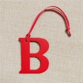 Detail of red leather letter B bag charm with matching strap on textured background - Letter B Red