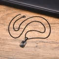 Macro detail of black stainless steel square pendant with radial texture on leather - Black Pendant With Box Chain