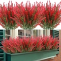 Outdoor window decor featuring red artificial lavender plants in green flower box - Red