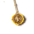 Macro shot of Saint Benedict gold pendant with yellow beads and detailed engraving - Bright Yellow