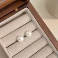 Primer plano de elegantes pendientes de perlas blancas sobre lino en caja de madera - 10mm