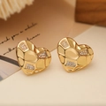 Dettaglio macro degli orecchini a cuore placcati oro 18K con trama trapuntata e zirconi - Stile Cuore Martellato / Oro