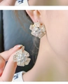 Detalle de los pendientes de flor plateados con cristales de circonita brillantes - Dorado