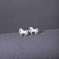 Detailed view of silver horse-shaped stud earrings with cutout design on textured background - Stud Earrings / Silver