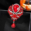 Vintage luxury brooch featuring a large red teardrop crystal and ornate floral silver setting - Red