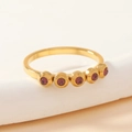 Macro shot of gold stainless steel ring featuring five purple stones in bezel setting - Gold/Purple Zirconia