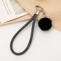 Détail d'une lanière tressée grise et d'un pompon en fourrure noire sur porte-clé - Noir