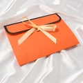 Sacchetto regalo arancione con bordo nero e fiocco beige su tessuto di seta bianca - Arancione