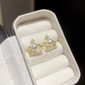 Detalle de pendientes de corona con perla blanca y circón en un joyero elegante - Diseño de Corona (HE30419) / Dorado-Perla Blanca