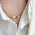 Close-up of gold SIS letter pendant necklace on snake chain worn with white shirt - SIS Necklace