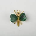 Butterfly brooch with gold alloy body and natural green malachite wings on white surface - Malachite