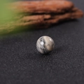 Polished 16mm natural stone sphere with grey and white swirl textures on a dark surface - Picasso Stone