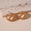 Detailansicht goldener Horn-Ohrringe mit Spiralstruktur auf einem Steinsockel - Goldene gerippte geometrische Creolen / Gold