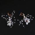 Close-up of handmade bridal ear clips with pearls and translucent flower petals - Clip-On Earrings / White