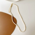 Dettaglio collana di perle a forma di S con chiusura dorata su pelle - Collana di perle d'acqua dolce irregolari