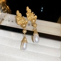 Primer plano de pendientes vintage dorados con flores de metal y perlas de gota - Dorado/Blanco Perla