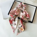 Vue détaillée d'un chouchou en satin rose à fleurs avec de longs rubans sur plateau - Grande Fleur Rose