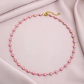 Detail of gold evil eye necklace with pink beads on a soft silk background - Pink