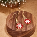 Festive gold earrings with red enamel snowflake pendants on a wooden display base - Red Round Plate Snowflake Style (E00918G)