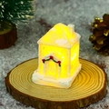 Detail of white glowing resin Christmas snow house with red bow and warm LED lights - Style A