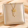 Elegant gold bow necklace with leaf-shaped zircon pendant displayed on champagne silk fabric - Gold Leaf Style (8011)