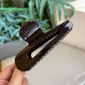 Dettaglio di una grande molletta per capelli marrone scuro lucido con design a goccia - Cioccolato