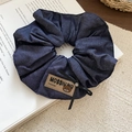 Detailaufnahme des Jeansblau Stoff-Haargummis mit Bären-Patch und schwarzem Schleifenband - Denim/Elastik / Scrunchie - Blau - Plissee