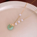 Detail der Ginkgoblatt-Anhänger mit Jade-Ring und violetten Perlen an Goldkette - Ginkgoblatt Imitation Jade Halskette