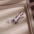 Detailed close-up of a silver violin brooch with red rhinestones in a silk gift box - Silver Red