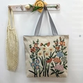 Beige canvas tote bag with colorful floral embroidery and black and white striped straps - Floral Scent