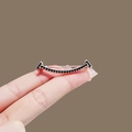 Smile shaped metal brooch pin with black gemstone inlay shown on a finger - 242# Smile Face