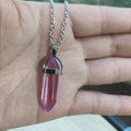 Handheld shot of a purple hexagonal crystal column pendant on a thin silver chain - Amethyst