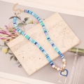 Detail of blue clay bead necklace featuring a sparkling heart pendant on marble stone - Mixed Blue