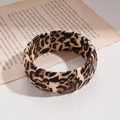 Makro-Detail des Lederarmreifens mit Leopardenmuster auf Vintage-Zeitungsuntergrund - Armreif-Braun-Breit