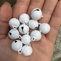 Witte 14mm gelakte metalen bellen voor DIY-knutselen en huisdieren getoond in hand - Wit